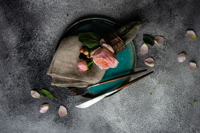 Top view delicate pink flowers on grey napkin and teal plate