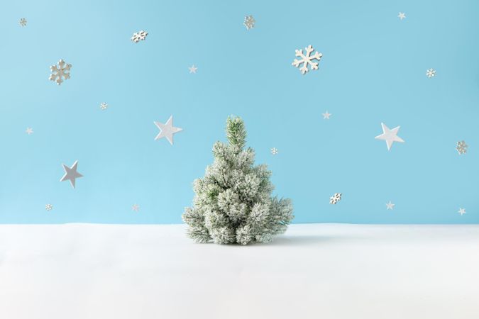 Snowy Christmas tree on blue background, with snowflakes
