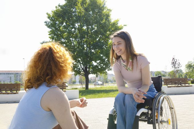 Woman kneeling down in front of her friend in a wheelchair
