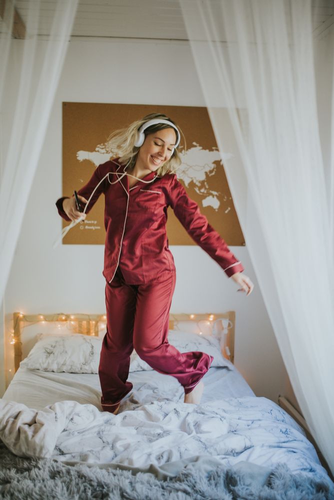 Woman with headphones dancing in bed