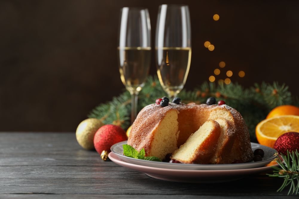 Cake with powdered sugar, berries and mint on wooden background, copy space