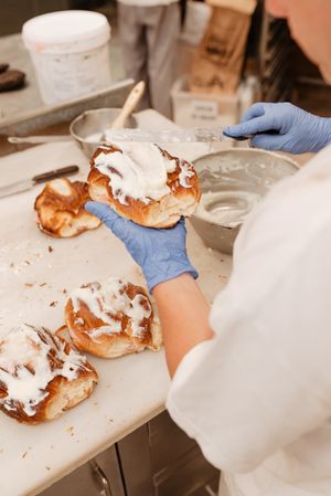 Crop baker smearing cream on bun