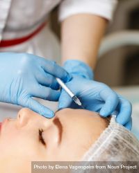 Cosmetologist at med spa injecting botox into wrinkles in female client 0yZgn5