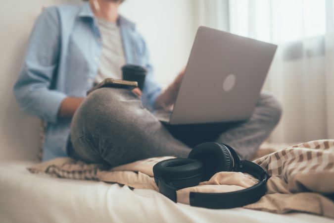 People sitting on bed holding coffee glass and using laptop