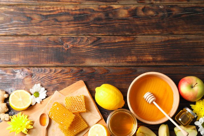 Flat lay with honey, flowers and fruits on wooden background, space for text