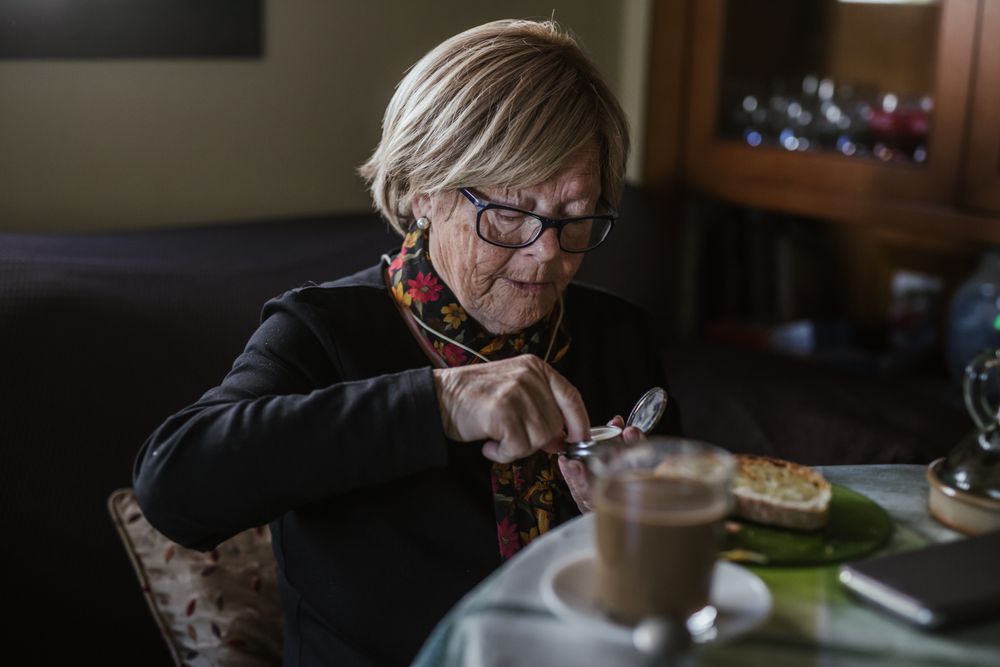 Older woman eating tablet from pill box