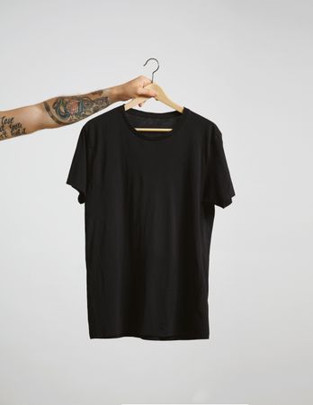 Arm holding a dark t-shirt on hanger