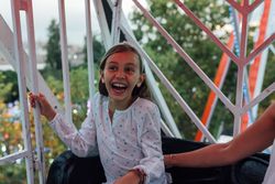 Cheerful girl riding Ferris wheel with parent