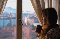 Woman enjoying hot beverage near fridge