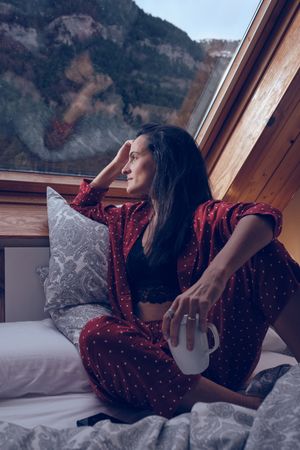Thoughtful woman looking out of window in bedroom