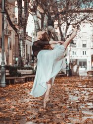 Ballerina in white skirt performing split in autumn street