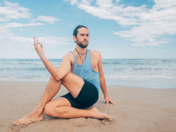 Man training yoga on beach
