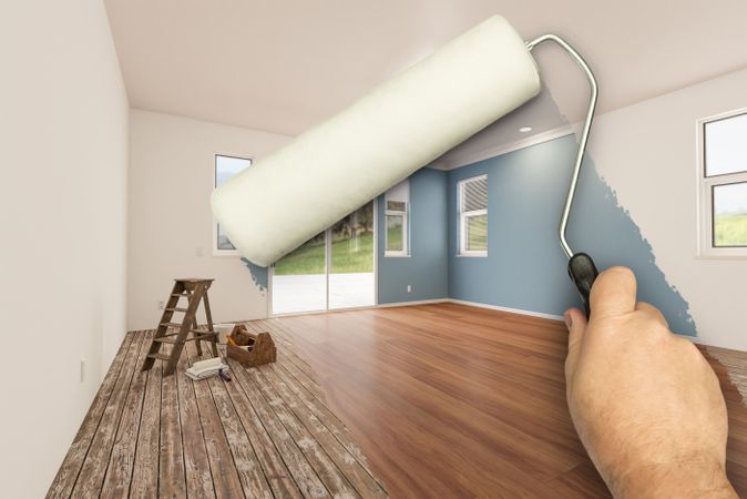 Before and After of Man Using A Paint Roller to Reveal Newly Remodeled Room with Fresh Green Paint, Coffered Ceiling and New Floors.