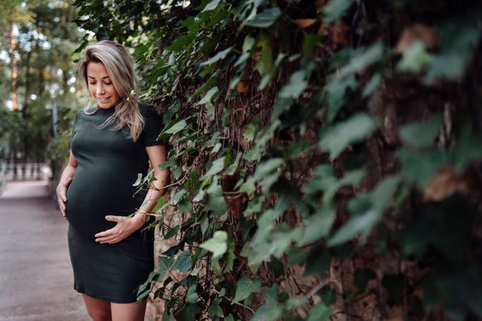 Charming pregnant woman standing on walkway in park