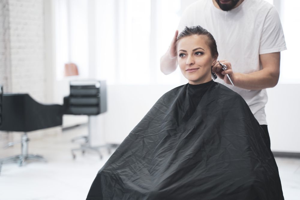 Hairdresser cuts woman's hair with scissors