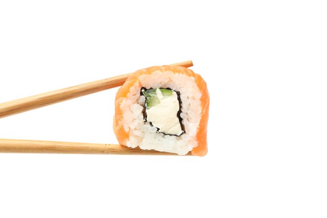 Chopsticks with sushi roll isolated on plain background