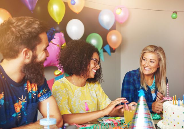 Group of smiling people sitting at table at birthday party