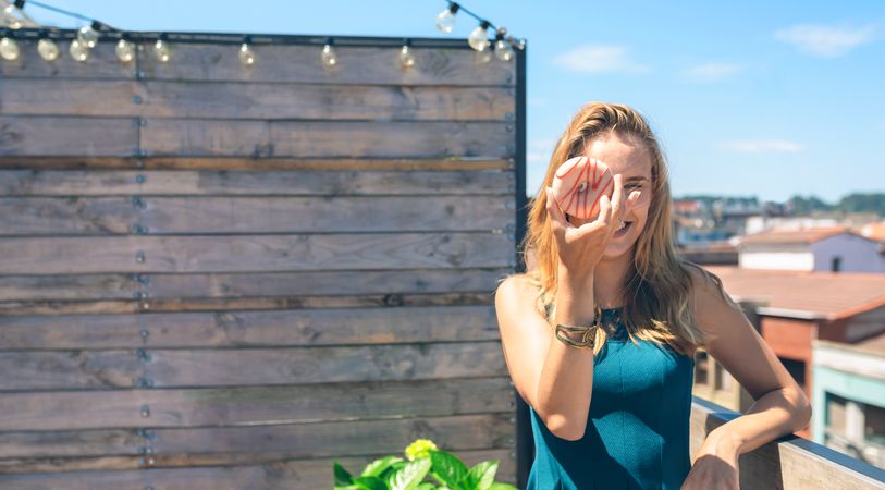 Funny woman posing covering her face with a doughnut