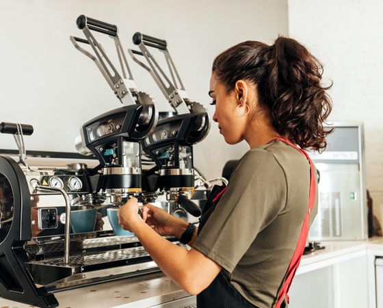 Female barista using a coffee machine to make an espresso