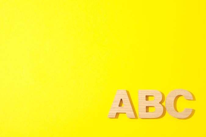Wooden letters of English alphabet on color background, space for text