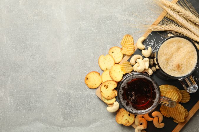 Beer, wheat and snacks on gray background