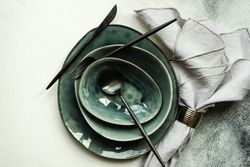 Top view of full table setting with bowls and plates on grey background