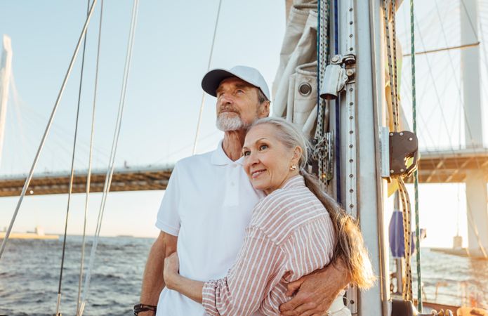 Older couple holding each other and enjoying the sunset on a boat