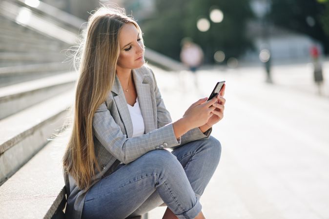 Woman sitting on steps checking phone