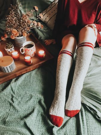Woman wearing long socks sitting in bed near tray