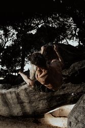 Man practicing rock climbing among large rocks in a forest