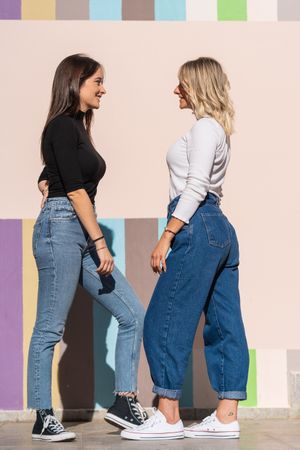 Happy girlfriends standing against painted urban wall