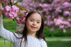 Portrait of young girl standing next to floral tree