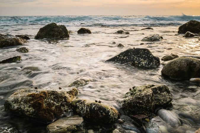 Stony seashore and waves at beautiful sunset