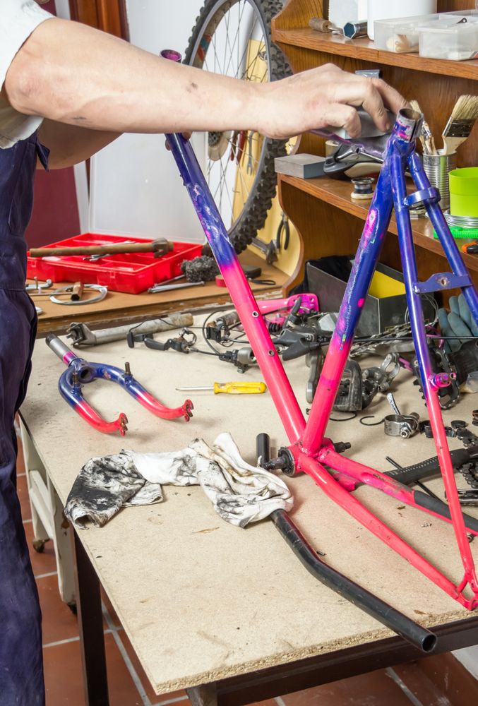 Hands of real bicycle mechanic sanding frame bike