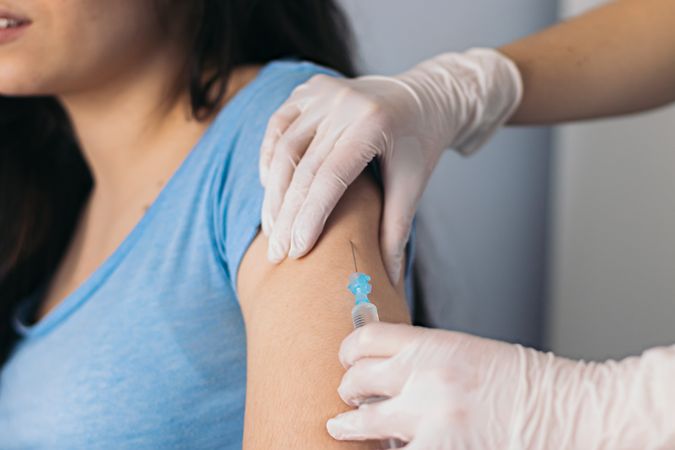 Vaccine in injection needle. Doctor working with patient's arm.