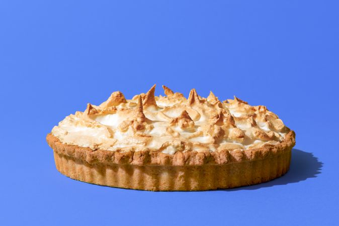 Lemon meringue pie isolated on a blue background
