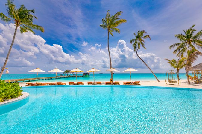 Beautiful clear pool on a resort with lounge chairs, parasols and a view out to the ocean