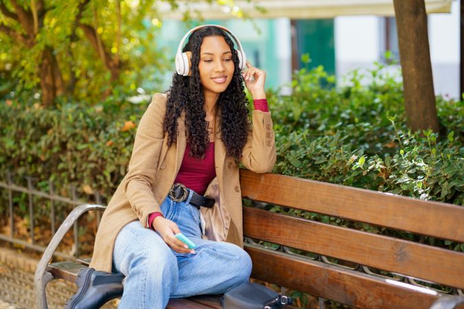 A Young Woman Is Relaxing in the Park While Enjoying Her Music with Headphones On