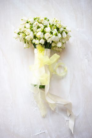 Snowdrop bouquet wrapped in translucent yellow ribbon on table