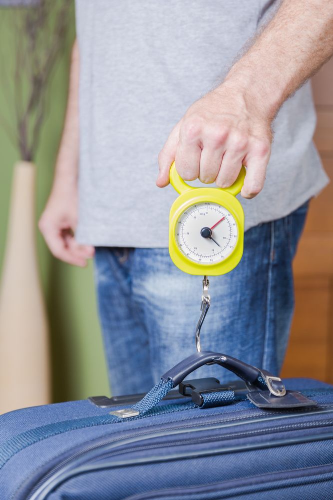 Man checking luggage weight with steelyard balance