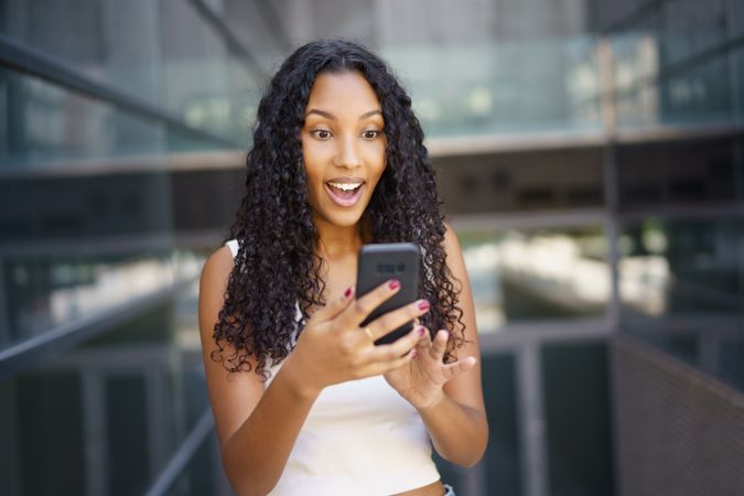 An Excited Young Woman Actively Engaging with Her Smartphone in a Trendy Modern Setting