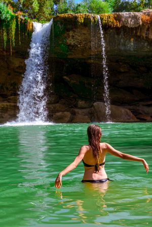 Anonymous female standing near amazing waterfall