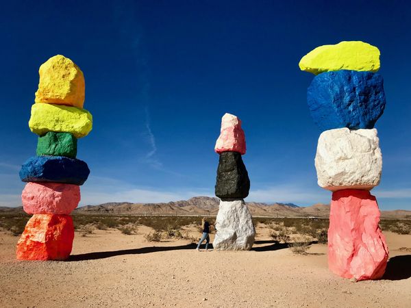 Person standing beside stacks of colorful rocks in desert