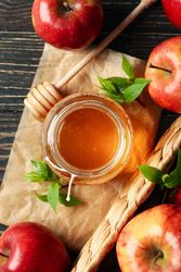 Looking down at pot of honey with dipper and apples, vertical