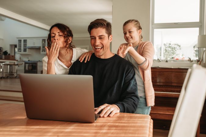 Family of three having a video call on laptop at home