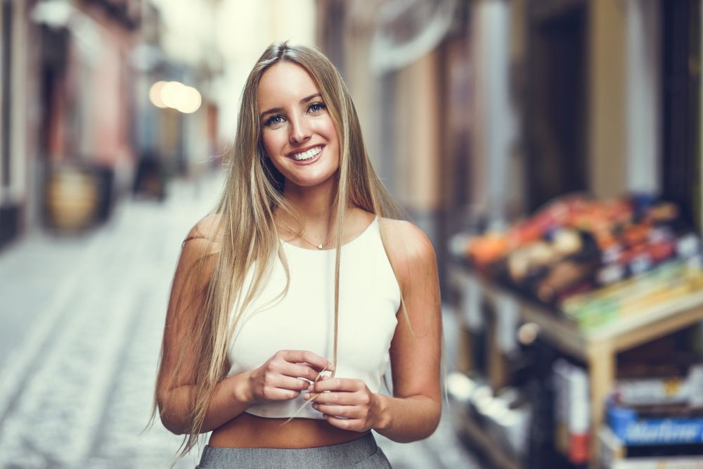 Smiling chic woman playing with hair in the street