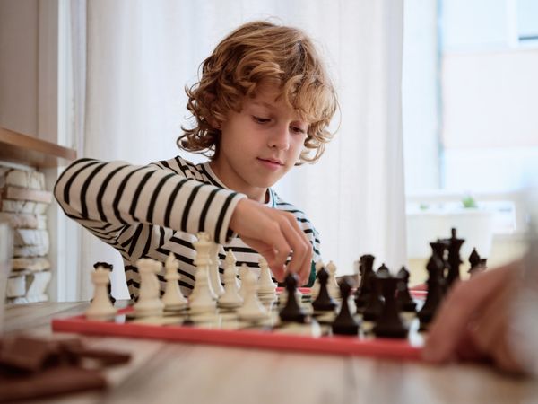 Boy playing chess with unrecognizable person