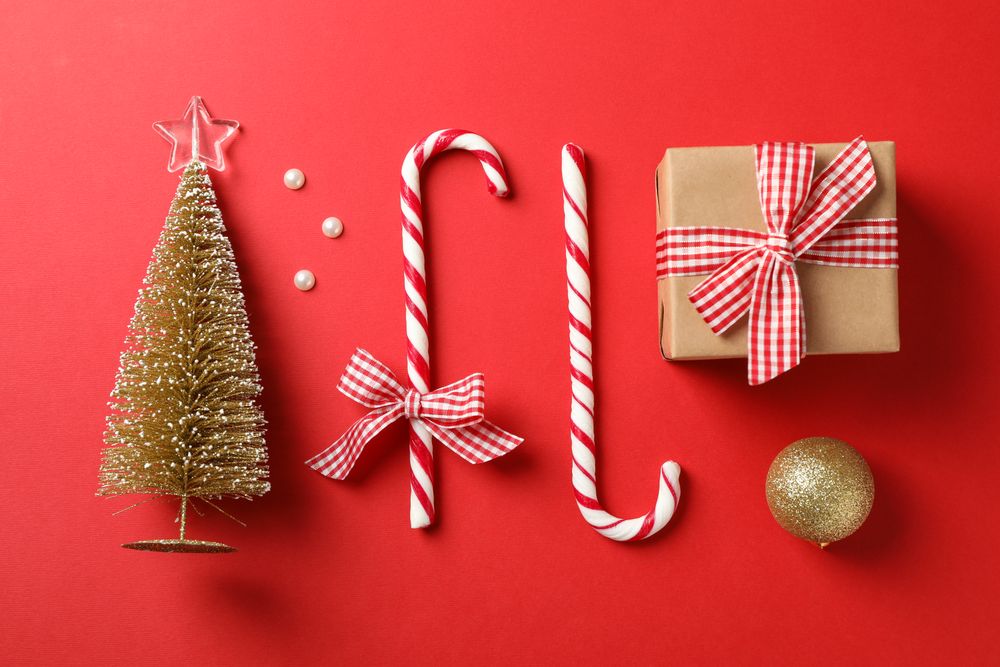 Candy canes and christmas accessories on red background, space for text
