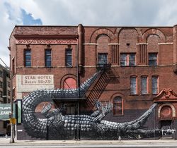 Whimsical alligator wall mural on red brick building y0vYGb