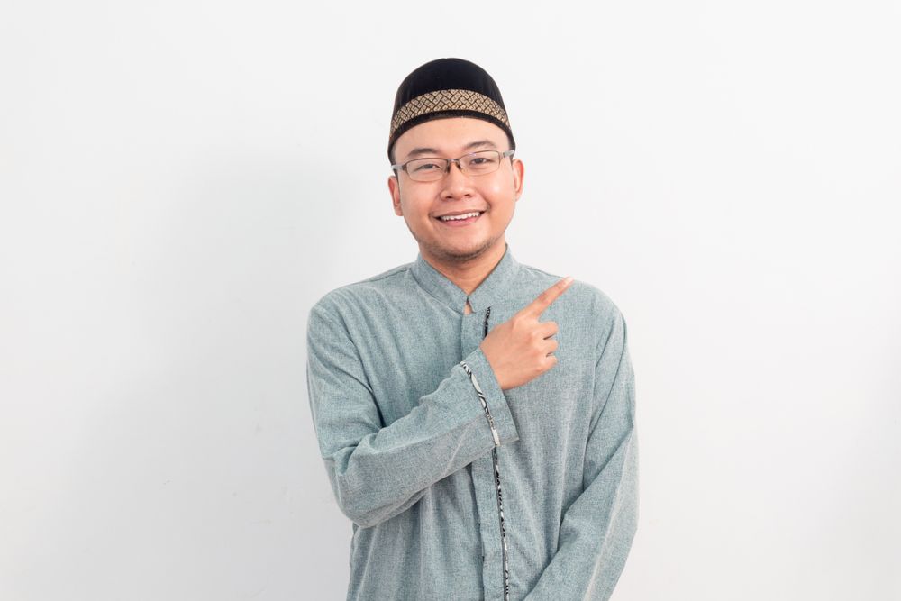 Asian Muslim man smiling doing pointing gesture in Ramadan
